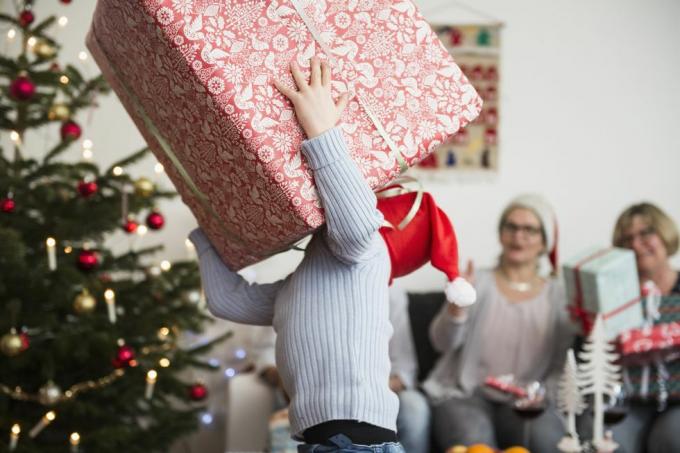 Anak kecil membawa kotak kardus besar saat Natal