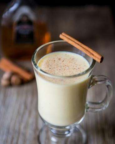 segelas eggnog dengan batang kayu manis