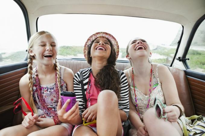 tiga gadis tertawa di kursi belakang kendaraan