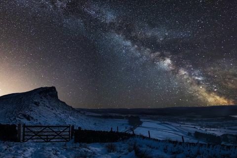 Gambar komposit Bima Sakti yang penuh dengan pemandangan salju yang tertutup Taman Nasional Peak District di Inggris