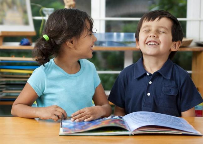 dua anak tertawa menikmati buku di sekolah