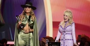 lainey wilson menerima penghargaan artis wanita tahun ini dari dolly parton di atas panggung di penghargaan akademi musik country ke-58