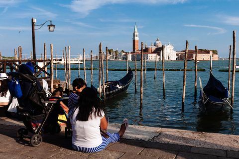 Turis duduk di tanah di Venesia sambil melihat Gereja San Giorgio