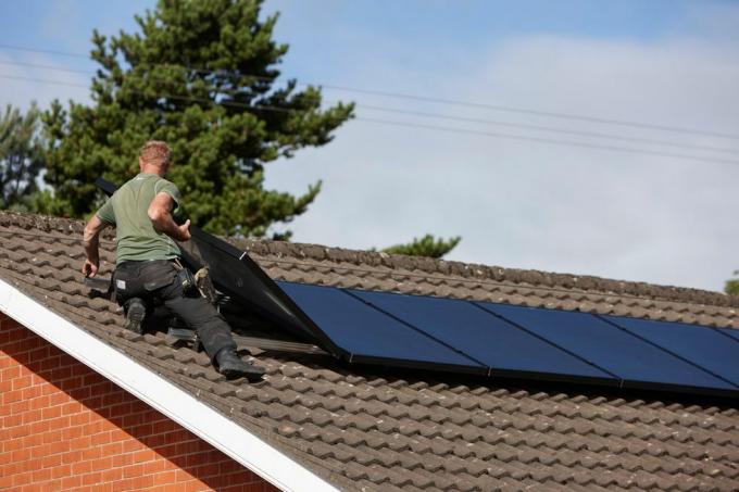 h0chn1 pria memasang susunan panel surya atap di instalasi panel surya domestik di Inggris