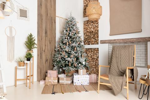 interior ruang tamu natal yang didekorasi dengan kotak hadiah pohon cemara yang indah di lantai, kayu bakar untuk perapian