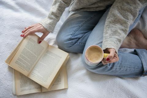 Wanita di tempat tidur dengan kopi dan buku