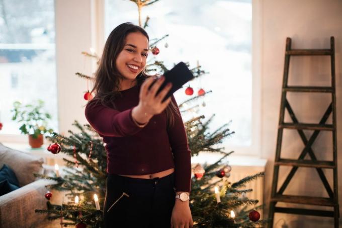 wanita mengambil selfie di depan pohon natal