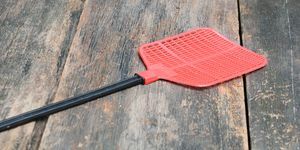 pemukul lalat merah pemukul lalat tunggal yang terbuat dari plastik dan tidak pernah gagal menangkap lalat di latar belakang lantai kayu