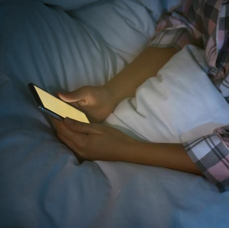 wanita menggunakan smartphone di tempat tidur pada malam hari, nomofobia jarak dekat dan masalah gangguan tidur