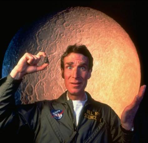 Ilmuwan Bill Nye dengan pakaian luar angkasa berdiri dari bulan