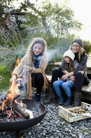 dua wanita dan gadis duduk di dekat lubang api, santai