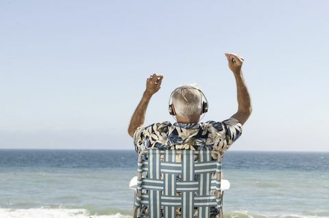 Orang tua yang senang mendengarkan musik yang menghadap ke laut