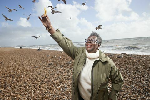 wanita senior memberi makan kentang goreng ke burung