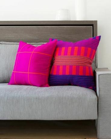 bantal neon pink di sofa abu-abu