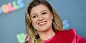 kelly clarkson tersenyum dengan gaun merah muda dan anting persegi hitam