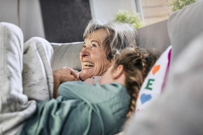 nenek ceria berbaring dengan cucu di sofa di rumah